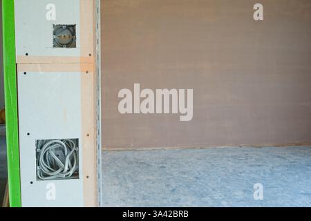 Une salle nouvellement plâtrée avec commutation électrique, premiers inserts de câblage. Travaux de construction finis avec une surface plane lisse de plâtre mince. Banque D'Images