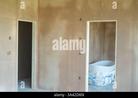 Une salle nouvellement plâtrée avec commutation électrique, premiers inserts de câblage. Travaux de construction finis avec une surface plane lisse de plâtre mince. Banque D'Images