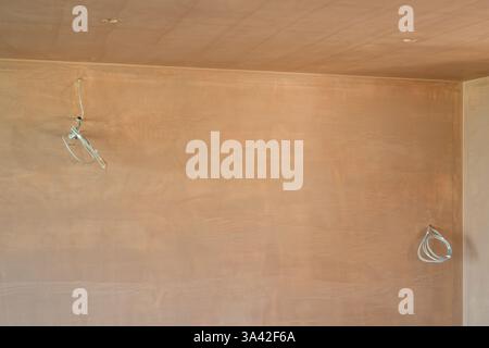 Une salle nouvellement plâtrée avec commutation électrique, premiers inserts de câblage. Travaux de construction finis avec une surface plane lisse de plâtre mince. Banque D'Images