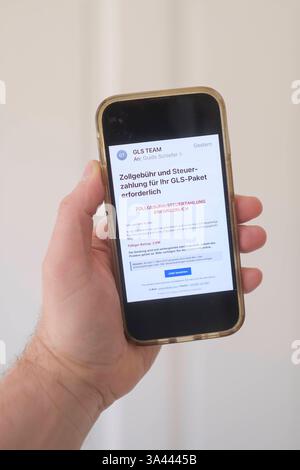 Hand mit Mobiltelefon auf dem eine betrügerische Email zu sehen ist, die eine angebliche Zollgebühr bzw Steuernachzahlung für ein Paket einfordert. *** Main avec un téléphone portable montrant un courriel frauduleux exigeant un prétendu paiement de frais de douane ou de taxes pour un colis. Nordrhein-Westfalen Deutschland, Allemagne GMS18789 Banque D'Images