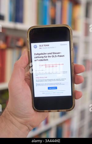 Hand mit Mobiltelefon auf dem eine betrügerische Email zu sehen ist, die eine angebliche Zollgebühr bzw Steuernachzahlung für ein Paket einfordert. *** Main avec un téléphone portable montrant un courriel frauduleux exigeant un prétendu paiement de frais de douane ou de taxes pour un colis. Nordrhein-Westfalen Deutschland, Allemagne GMS18790 Banque D'Images