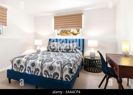 Une chambre confortable avec un lit confortable, un bureau élégant, une chaise assortie et des lampes élégantes offrant un éclairage doux Banque D'Images