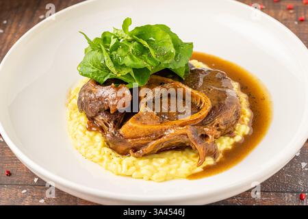 Osso buco gastronomique avec risotto au safran et légumes verts frais sur une assiette Banque D'Images