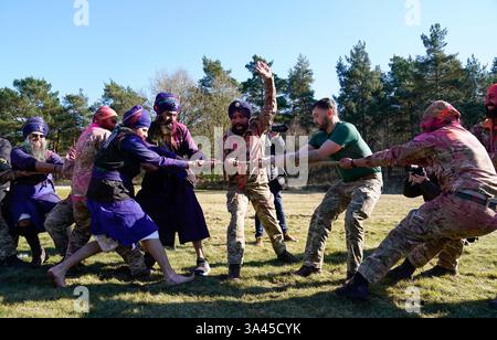 Des soldats sikhs de l'armée britannique et des membres de Bhudda Dal UK participent à une compétition de remorqueurs de guerre pendant le festival militaire Sikh Holla Mahalla, à la garnison d'Aldershot, dans le Hampshire. Le festival Hola Mahalla, vieux de plusieurs siècles, célèbre les traditions martiales sikhs et promeut le courage, la préparation et la préparation. Date de la photo : mardi 18 mars 2025. Banque D'Images