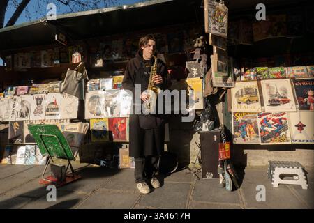 Paris, France. 18 mars 2025. Un vendeur de livres joue du saxophone le long de la Seine le 18 mars 2025 à Paris. (Crédit image : © Bryan Smith/ZUMA Press Wire) USAGE ÉDITORIAL SEULEMENT! Non destiné à UN USAGE commercial ! Banque D'Images