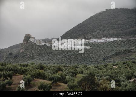 Un charmant village blanc niché sur une colline à Solera, en Espagne, entouré d'oliveraies luxuriantes et de montagnes brumeuses, créant un paysage rural serein Banque D'Images