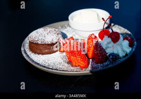 Assiette à dessert avec moelleux au chocolat, une boule de glace à la vanille, des fraises, de la crème fouettée et glacée avec du sucre en poudre, vieille ville de Bruxelles, br Banque D'Images