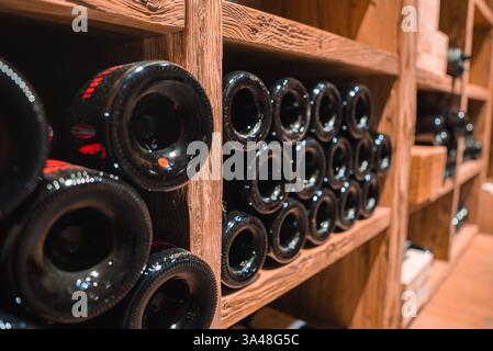 Cave à vin soigneusement arrangée avec étagères en bois et éclairage chaud Banque D'Images