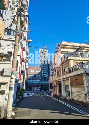 Petite rue arrière à Asakusa, Tokyo avec des maisons, des immeubles d'appartements et un ciel bleu clair. Banque D'Images