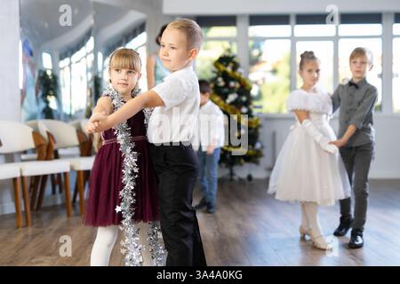 Tween garçon et fille exécutant la valse pendant l'événement de Noël à l'école Banque D'Images