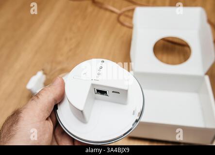 Paris, France - 17 juin 2021 : une main tient un appareil réseau blanc moderne avec des ports visibles et des voyants lumineux, fraîchement déballé de son minimaliste Banque D'Images