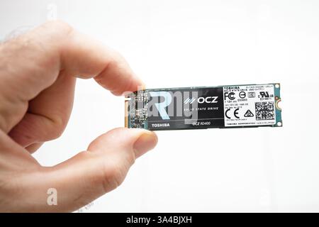 Paris, France - 3 février 2020 : une main tient soigneusement un disque SSD OCZ RD400, marqué de la marque Toshiba et de diverses étiquettes de certification. Banque D'Images