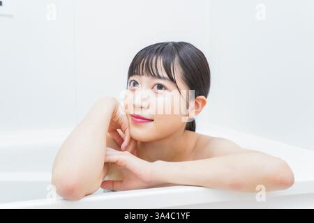 Jeune femme trempant dans l'eau chaude dans le bain Banque D'Images