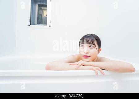 Jeune femme trempant dans l'eau chaude dans le bain Banque D'Images