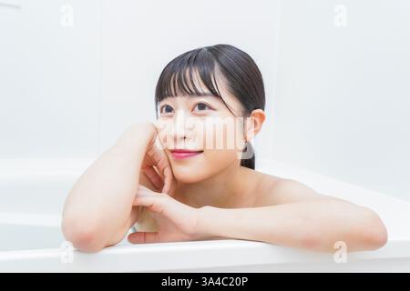 Jeune femme trempant dans l'eau chaude dans le bain Banque D'Images