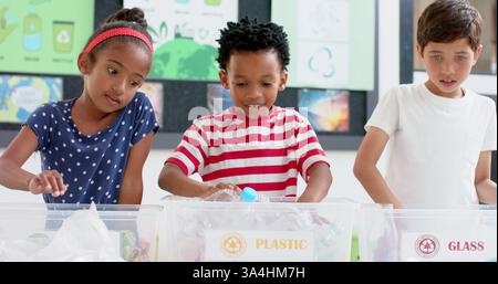 À l’école, les enfants trient les bouteilles en plastique dans des bacs de recyclage, apprennent la durabilité Banque D'Images