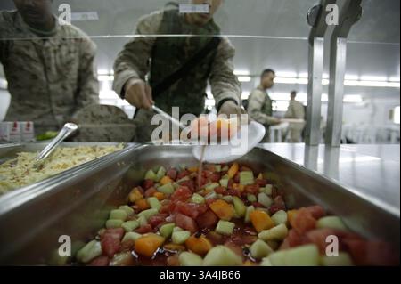 04 juillet 2004 ; Camp Fallujah, Irak ; Un Marine ramasse une cuillerée de fruits mélangés dans son assiette le 4 juillet 2004 au Camp Fallujah, Irak chow Hall. Les marins et les marins ont eu droit à des steaks, des hamburgers, des hot-dogs et d'autres aliments traditionnels pour les vacances. Banque D'Images
