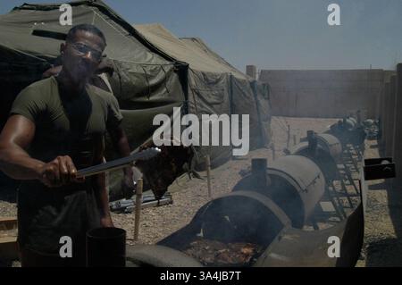 04 juil. 2004 ; Camp Fallujah, Irak ; Sgt. Maître ALBIS DELROSARIO, officier sous-officier en charge du Centre de repos et de relaxation, montre une dalle de côtes avant que le centre ne soit inondé de Marines, marins et soldats avec l'équipe de combat régimentaire 1 pour leur jour de l'indépendance au Camp Fallujah. Banque D'Images