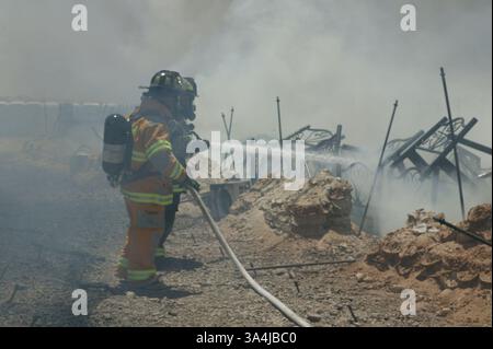 07 juillet 2004 ; Camp Al Asad, Irak ; les pompiers du corps des Marines et de l'armée ont combattu un incendie pendant plus d'une heure dans la chaleur et à travers la fumée au Camp Al Asad, le 7 juillet. Les flammes étaient aussi proches que 10 pieds d'atteindre d'autres tentes. Un total de 141 Marines du 3e Bataillon, 4e Régiment de Marines ont perdu tous leurs biens. Banque D'Images