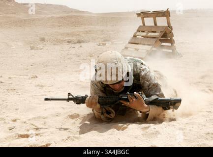 10 juillet 2004 ; Al Asad, Irak ; le Cpl TRAVIS J. MILLER, garde, Force de sécurité du Centre de commandement aérien tactique, escadron 3 du quartier général de l'escadre des Marines, 3e Escadre d'avion des Marines, franchit à basse altitude le terrain désertique difficile d'un point de tir à l'autre à Al Asad, Irak, le 10 juillet. Le natif d'Altoona, Pa., âgé de 28 ans, a pu rafraîchir ses connaissances sur les armes et les tactiques d'infanterie pendant l'entraînement au tir et aux manœuvres. Banque D'Images