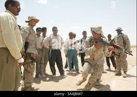 14 juillet 2004 ; Camp Al Asad, Irak ; 1er sergent Octaviano GALLEGOS Jr., 37 ans, compagnie B, 3e bataillon amphibien d'assaut, montre aux recrues de la police des frontières irakienne comment perquisitionner et saisir correctement un bâtiment, tandis que lance le caporal Nicholas G. Bibby, 21 ans, explique le processus aux Iraquiens le 14 juillet. Le cours, qui est le premier à l'Académie de police d'Al-Assad, est un cours de 10 jours qui leur permettra de patrouiller les frontières occidentales de l'Irak. Banque D'Images