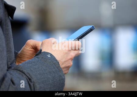 Smartphone dans les mains masculines, homme utilisant le téléphone portable sur la rue de la ville au printemps Banque D'Images