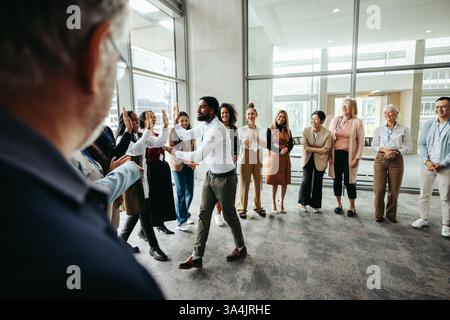 Patron célébrant avec les employés, donnant haut-cinq dans un bureau moderne. L'équipe profite d'un moment de reconnaissance et de réussite dans un environnement de travail Banque D'Images