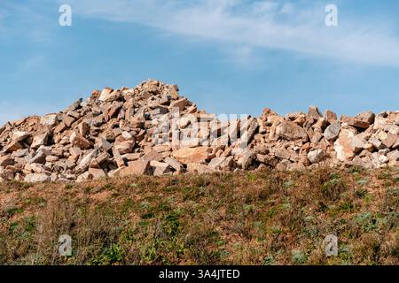 Une grande pile de rochers se trouve sur une colline herbeuse. Les roches varient en taille et en forme, formant une caractéristique naturelle robuste sur la toile de fond d'un brillant Banque D'Images