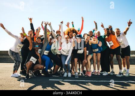 Un groupe de coureurs enthousiastes célèbrent ensemble après avoir participé à un événement communautaire animé. Mettant en vedette des personnes d'âges et d'horizons différents Banque D'Images