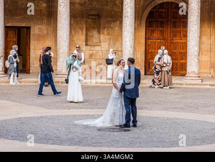 Un groupe de jeunes femmes musulmanes portant le foulard prennent des photos d'un couple nouvellement marié qui pose pour le photographe officiel dans la cour d'un ancien bâtiment du centre de Grenade en Espagne. Banque D'Images
