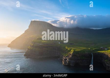Vue aérienne de la cascade de Mulafossur avec le petit village de Gasadalur. Île de Vagar, Îles Féroé, Danemark, Europe. Banque D'Images
