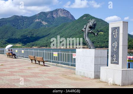 Comté de Damyang, Corée du Sud - 23 septembre 2020 : une statue de dragon en bronze se dresse au bord du lac Damyang, avec la montagne Jeonggak en arrière-plan. Banque D'Images