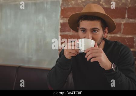 Homme dans le chapeau appréciant le café à la mode, se détendre et se détendre, copier l'espace Banque D'Images