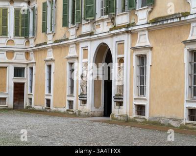 Colorno, Italie 1er mars 2025 Cour pavée, entrée voûtée et statues au Palais de Colorno, mettant en valeur l'architecture et l'histoire italiennes Banque D'Images