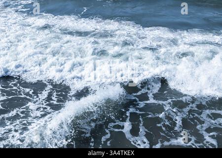 Les vagues de l'océan qui déferlent de mousse contre le rivage montrent l'énergie dynamique de la nature et la beauté en mouvement Banque D'Images