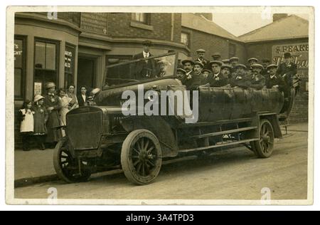 Original WW1 carte postale de Daimler charabanc de la société Nottingham, Barton Bros Beeston - signe à l'avant du véhicule. Dans la vitrine se trouve une affiche demandant « L'Angleterre attend de chaque homme qu'il fasse son devoir » et les ourlets à hauteur de la cheville indiquent la photographie datée vers 1917 - 1919. Les hommes ont l'air sombres et portent un chrysanthème dans leurs revers, comme le sont certaines des passantes. Deux des hommes ont une pulvérisation de fleurs plus élaborée 'boutonnière'. Est-ce une sortie de souvenir ou une fête de mariage de marié et meilleur homme - (les gens ne souriaient pas beaucoup dans les premières photos) ? Beeston, Nottingham, Royaume-Uni Banque D'Images