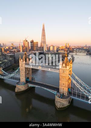Vue élevée du Tower Bridge sur la Tamise au lever du soleil, mettant en évidence la chaussée vide, l’Hôtel de Ville et le gratte-ciel The Shard à Londres Banque D'Images