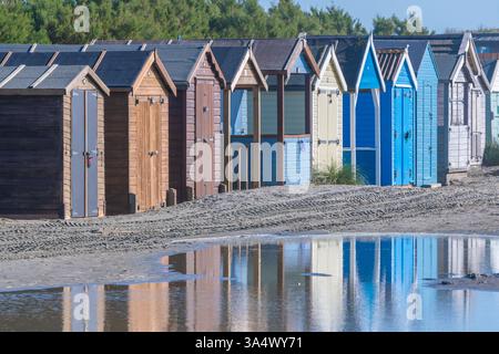 Cabanes de plage multicolores avec un reflet sur la magnifique plage de West Wittering dans le West Sussex Banque D'Images