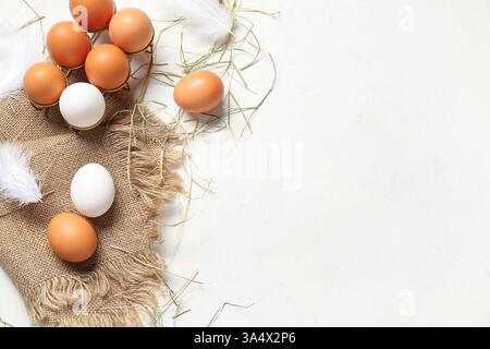 Support avec des œufs de poule crus et sac de tissu sur fond blanc Banque D'Images