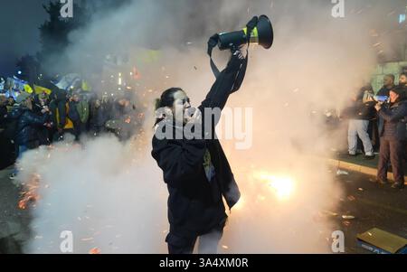 JÉRUSALEM - 19 MARS : un manifestant antigouvernemental scande des slogans à travers un corne de taureau à côté d'un incendie lors d'une manifestation près de la résidence privée du premier ministre Benjamin Netanyahou le 19 mars 2025 à Jérusalem, en Israël. La protestation intervient pendant des tensions croissantes alors que Netanyahu annonce son intention de licencier Ronen Bar, directeur du Shin Bet, en raison d'une « méfiance persistante » en temps de guerre. Banque D'Images