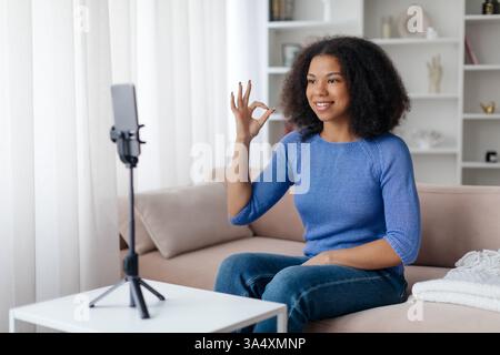 Concept de vlogging. Jeune femme noire souriante capturant une vidéo à la maison, Banque D'Images
