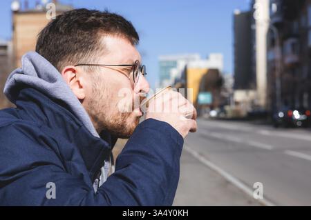 Jeune homme enjoying coffee outdoors Banque D'Images