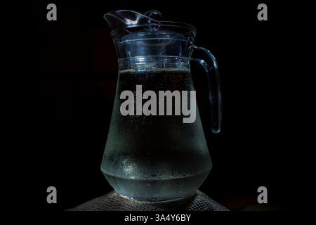 Pichet en verre d'eau sur la table. Place pour le texte, pour la publicité, les menus et les documents imprimés. Fond sombre. Banque D'Images