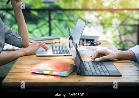 Deux jeunes femmes d'affaires assises à table à l'aide d'un ordinateur portable et d'un smartphone dans un café-restaurant. Blogueurs freelancers travaillant. Femme utilisant un smartphone, Busin Banque D'Images