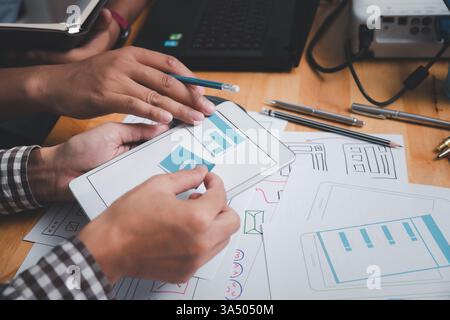 Les concepteurs d'interface utilisateur ou d'UX conçoivent sur leur projet prototype de mise en page d'applications pour smartphone. Banque D'Images