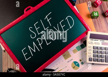 Tableau noir affichant du texte indépendant entouré de fournitures de bureau et de documents sur un bureau en bois. Banque D'Images