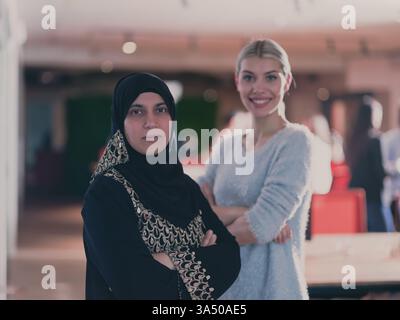 Femme d'affaires du moyen-Orient en hijab se tient avec un collègue caucasien dans le bureau. L'image reflète le travail d'équipe et le leadership diversifiés et multiculturels dans un milieu de travail moderne. Idéal pour les thèmes d'entreprise, de démarrage et de collaboration. Banque D'Images