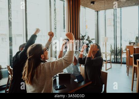 Groupe de professionnels divers levant leurs mains dans la célébration. Une image d'équipe d'entreprise moderne qui véhicule le travail d'équipe, la réussite et une culture positive en milieu de travail. Idéal pour la réussite commerciale, la collaboration et les récits de croissance de l'entreprise. Banque D'Images