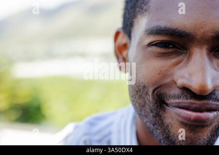 Homme afro-américain souriant profitant de vacances en plein air, se sentant détendu et content Banque D'Images