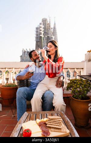 Multiracial beau couple heureux d'amoureux datant sur le balcon sur le toit à la Sagrada Familia, Barcelone - personnes multiethniques ayant un apéritif romantique sur Banque D'Images